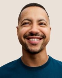 Retrato de una persona del equipo de Apple Retail sonriendo con cabello corto oscuro y barba.
