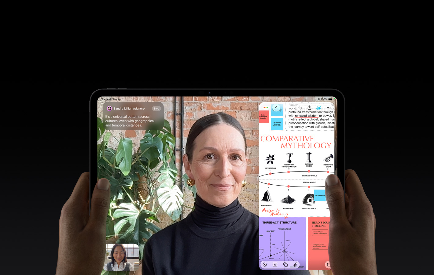 iPad Pro, esikülg, kosmosemust värv, mõlemad käed hoidmas seda horisontaalpaigutuses, ekraani must serv, ümarad nurgad, ekraanil tõlgitakse reaalajas FaceTime’i vestlust ning haridusrakendus näitab esitlust “Võrdlev mütoloogia” teksti, diagrammide ja käsitsi kirjutatud märkmetega